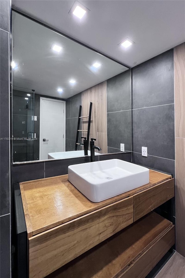 full bathroom featuring a shower stall, vanity, backsplash, and tile walls