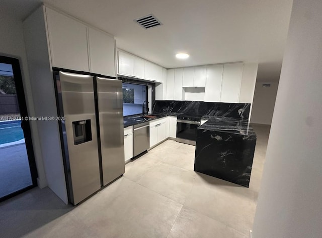 kitchen with dark countertops, white cabinetry, stainless steel appliances, and visible vents