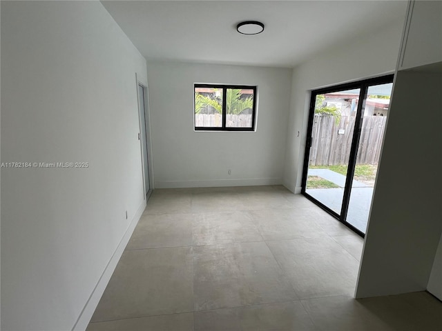 unfurnished room featuring baseboards, concrete flooring, and plenty of natural light