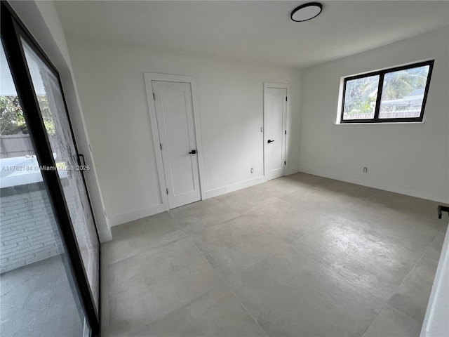 unfurnished bedroom with concrete flooring and baseboards