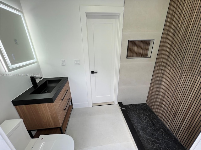 bathroom featuring tile patterned floors, toilet, vanity, and tiled shower