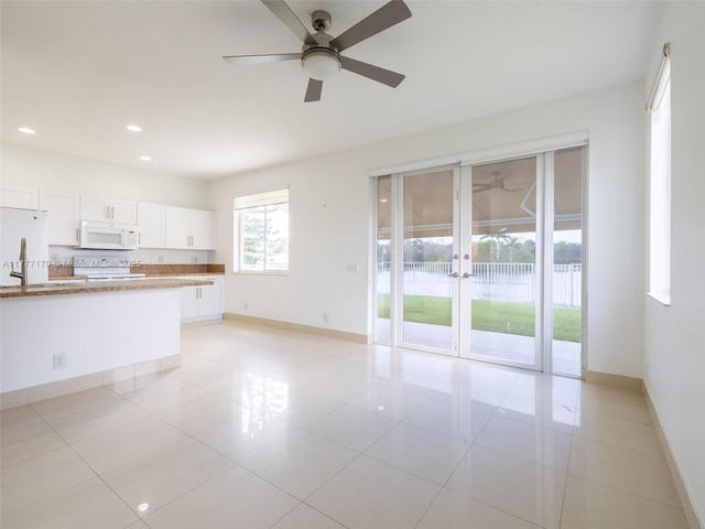 unfurnished living room featuring light tile patterned floors, french doors, baseboards, and a ceiling fan