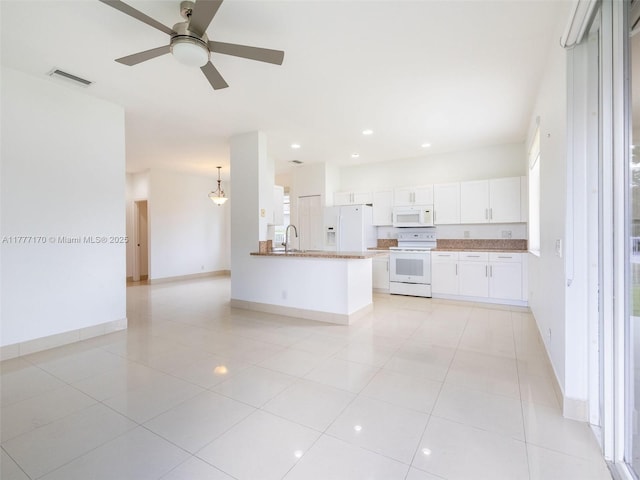 kitchen featuring white appliances, light tile patterned floors, white cabinets, visible vents, and a sink
