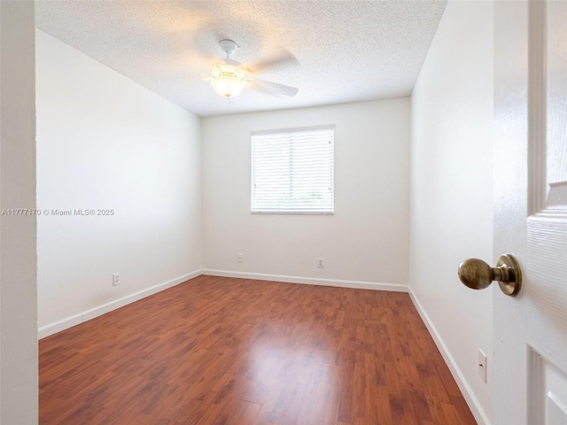 empty room with a textured ceiling, wood finished floors, ceiling fan, and baseboards