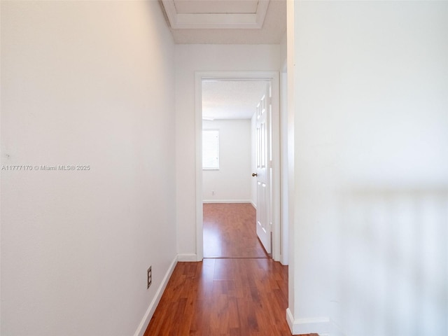 hall with baseboards, attic access, and wood finished floors