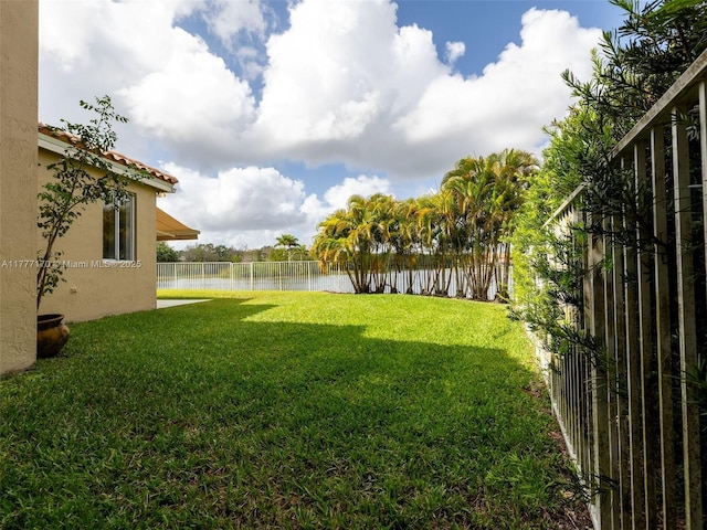 view of yard featuring a water view and a fenced backyard
