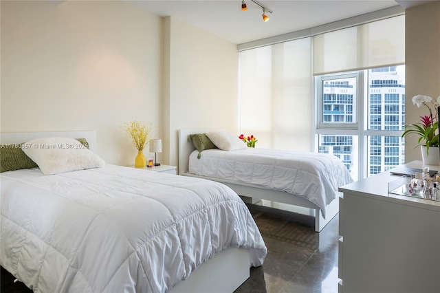 bedroom featuring finished concrete flooring and rail lighting