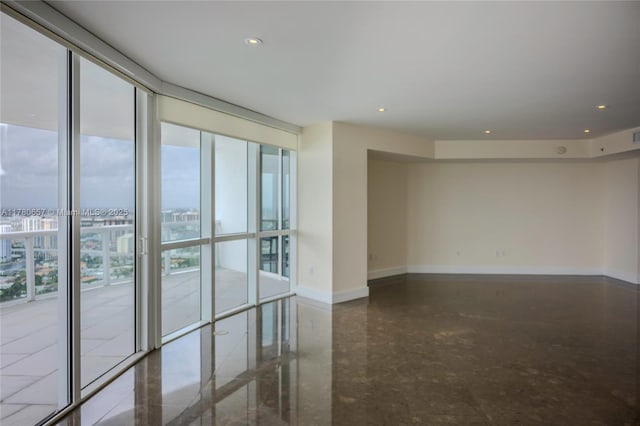 empty room featuring baseboards, recessed lighting, and expansive windows