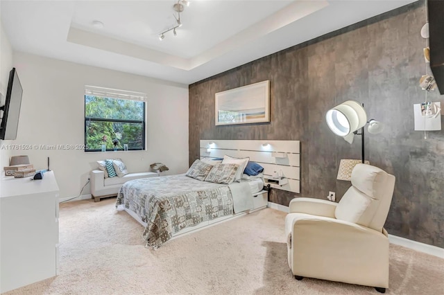 carpeted bedroom with a tray ceiling and baseboards