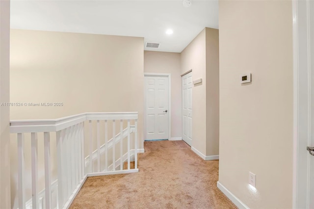 hallway featuring an upstairs landing, visible vents, baseboards, and carpet