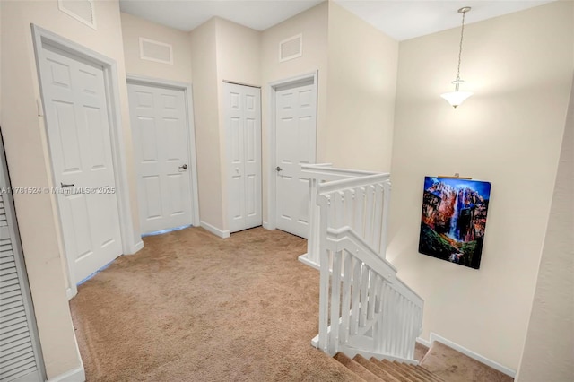 hallway featuring visible vents, baseboards, and an upstairs landing