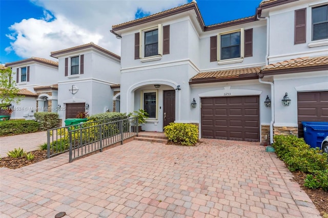 view of front of property with a garage, stucco siding, a tile roof, and decorative driveway
