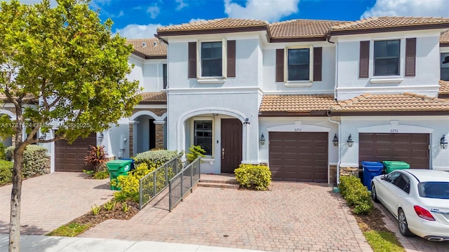 view of front of house featuring driveway, stucco siding, an attached garage, and a tile roof