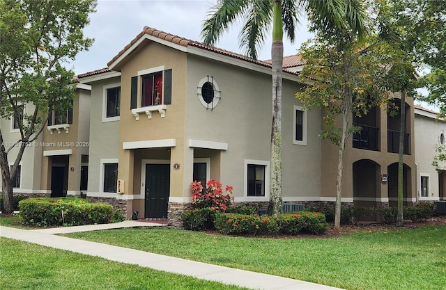 view of front of property with a tiled roof, a front yard, and stucco siding