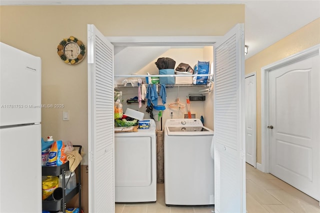 laundry area with washing machine and dryer, light tile patterned floors, and laundry area
