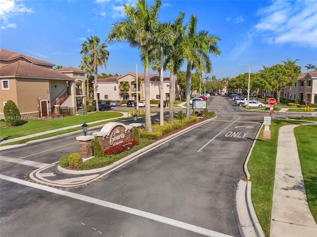 view of road with a residential view, sidewalks, traffic signs, street lighting, and curbs