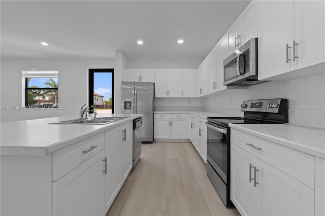 kitchen with light wood-type flooring, recessed lighting, light countertops, appliances with stainless steel finishes, and a sink