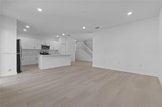 unfurnished living room featuring light wood-type flooring, baseboards, visible vents, and recessed lighting