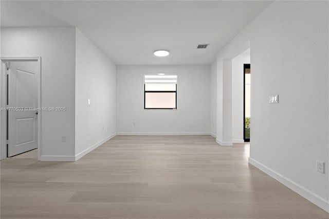 unfurnished room with visible vents, light wood-type flooring, and baseboards