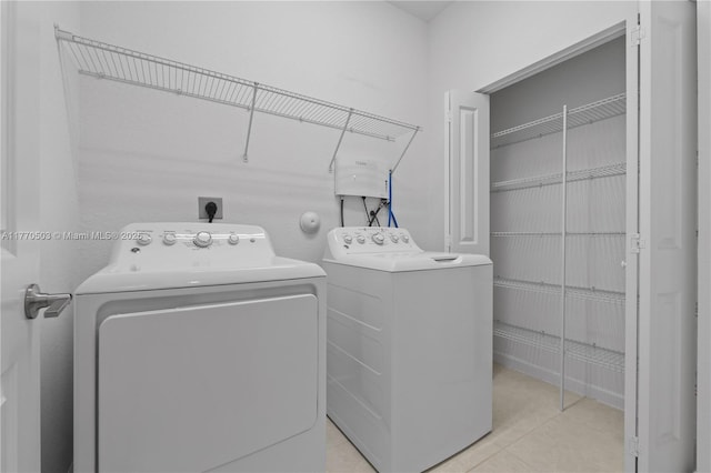 clothes washing area featuring laundry area, washing machine and clothes dryer, and light tile patterned floors