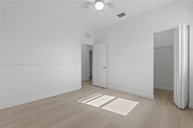 unfurnished bedroom with light wood-style floors, a spacious closet, and visible vents