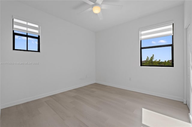 spare room featuring light wood-style flooring, ceiling fan, baseboards, and plenty of natural light