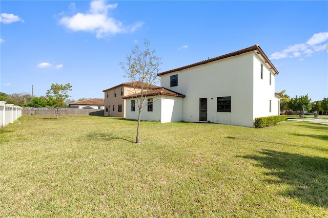 back of property featuring a yard, stucco siding, fence, and a tile roof