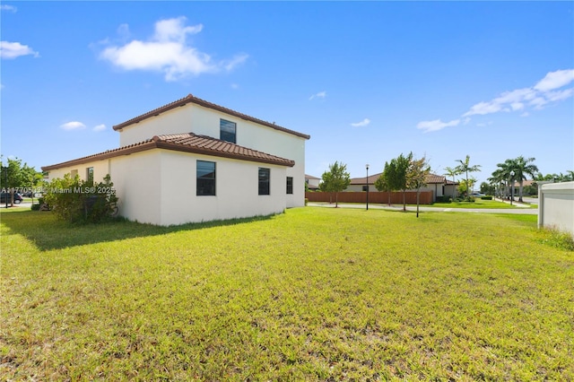 exterior space with a yard, stucco siding, and a tile roof
