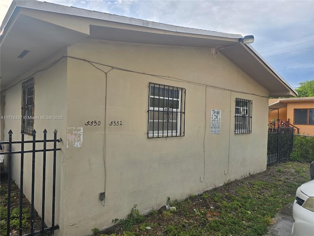 view of property exterior featuring stucco siding and fence