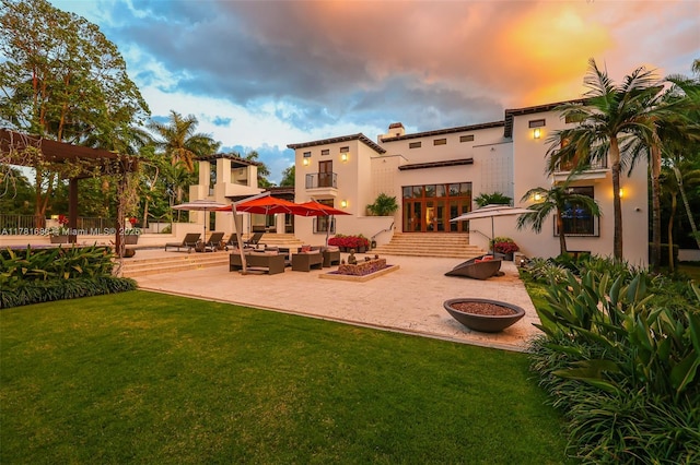 555 Arvida Pkwy, Coral Gables, FL 33156 - back of property at dusk featuring a patio area, stucco siding, french doors, and a yard
