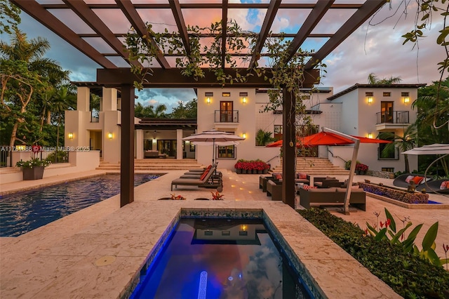 555 Arvida Pkwy, Coral Gables, FL 33156 - back of property at dusk with outdoor lounge area, a pergola, an in ground hot tub, and a balcony
