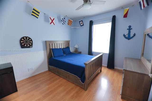 266 Iris Dr, Jupiter, FL 33458 - bedroom with light wood-style flooring, ceiling fan, baseboards, and a wainscoted wall