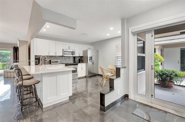 1237 NW 52nd Way, Deerfield Beach, FL 33442 - kitchen with tasteful backsplash, a breakfast bar, baseboards, a peninsula, and stainless steel appliances