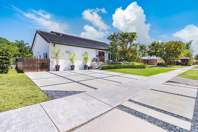 view of front facade with concrete driveway, stucco siding, a garage, and a front yard