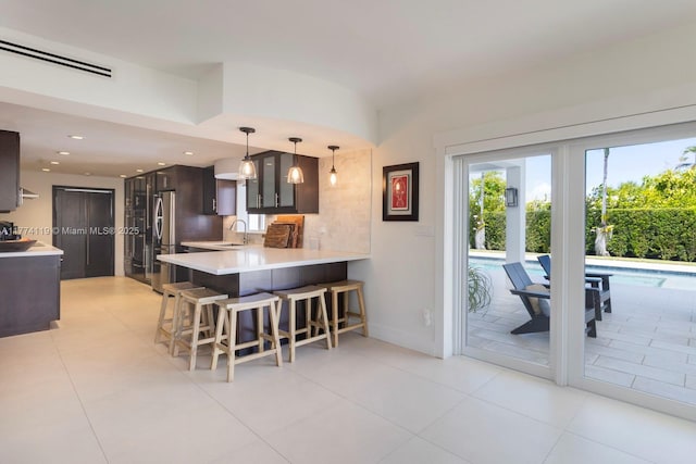 kitchen featuring visible vents, a sink, light countertops, freestanding refrigerator, and a breakfast bar