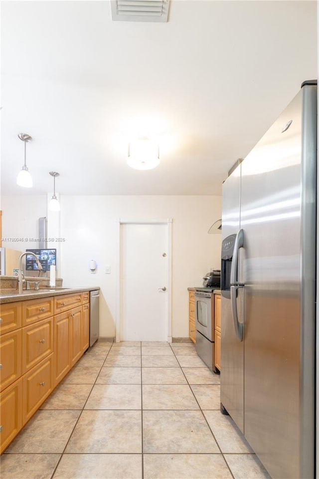 kitchen featuring stainless steel appliances, a sink, light tile patterned floors, and pendant lighting
