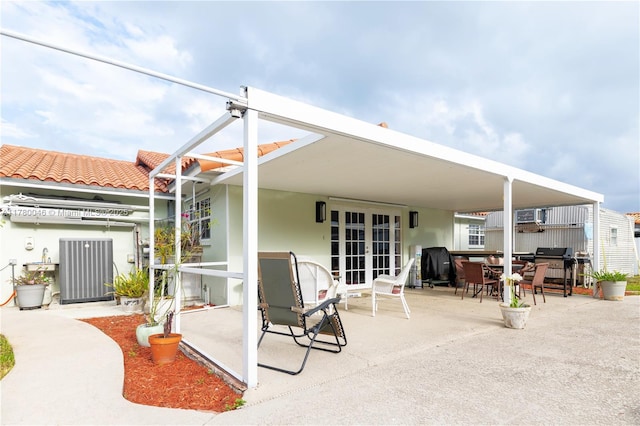 back of house with french doors, a patio, a tile roof, outdoor dining area, and stucco siding