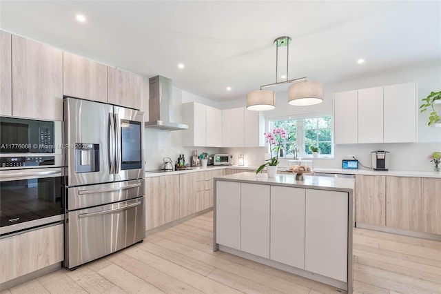 kitchen with wall chimney range hood, black appliances, and modern cabinets