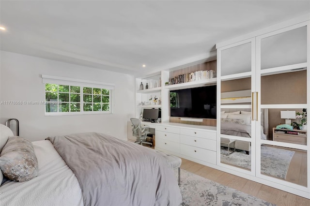 bedroom with wood finished floors, built in study area, and recessed lighting