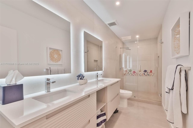 bathroom featuring a shower stall, double vanity, a sink, and toilet
