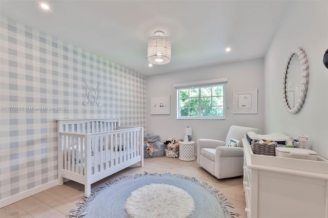 bedroom with a nursery area, light wood finished floors, recessed lighting, and wallpapered walls