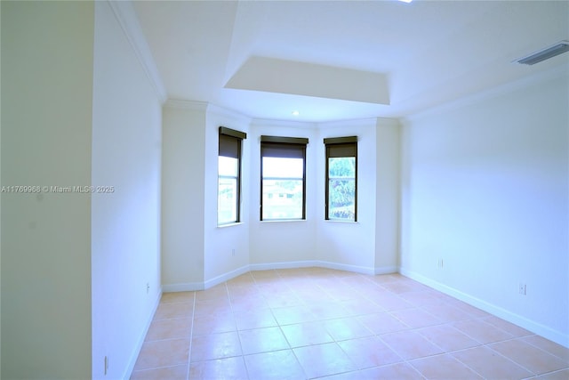 empty room with baseboards, visible vents, light tile patterned flooring, crown molding, and a tray ceiling