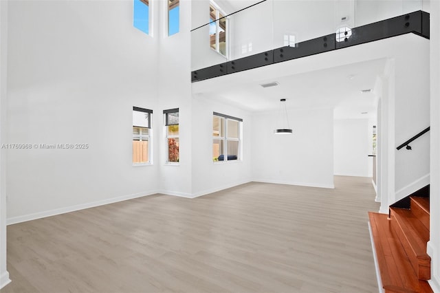 16477 SW 67th Ter, Miami, FL 33193 - unfurnished living room with plenty of natural light, light wood-type flooring, stairs, a towering ceiling, and baseboards
