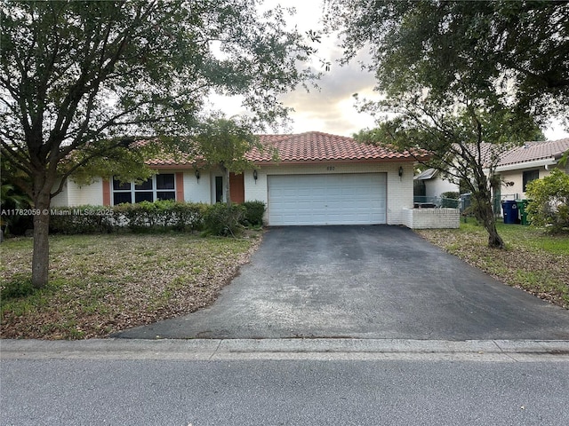 view of front of property with a tiled roof, a garage, driveway, and brick siding