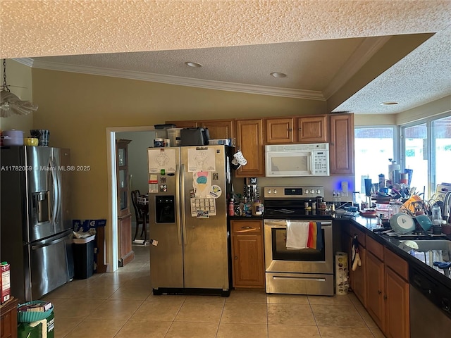 kitchen with light tile patterned floors, a textured ceiling, ornamental molding, and appliances with stainless steel finishes