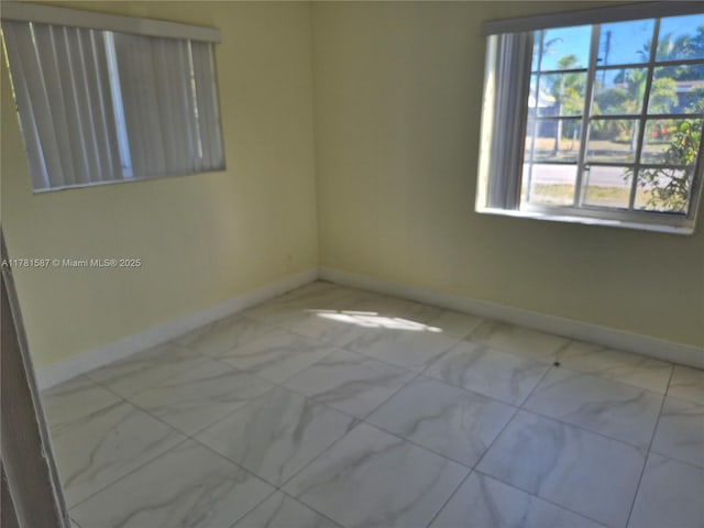 unfurnished room with a wealth of natural light and baseboards