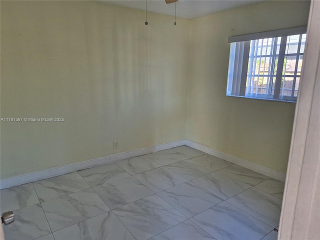 empty room featuring marble finish floor and baseboards