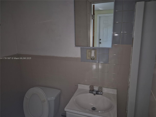 bathroom featuring vanity, tile walls, and toilet
