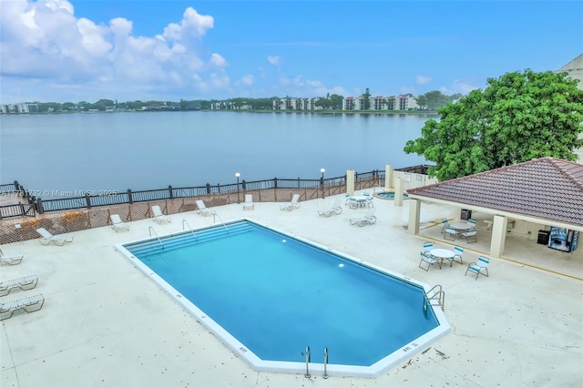 pool with fence, a patio, and a water view