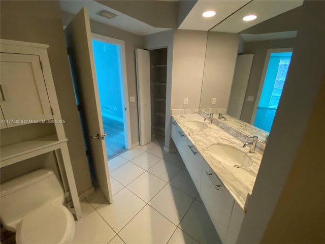 bathroom featuring toilet, double vanity, a sink, and tile patterned flooring